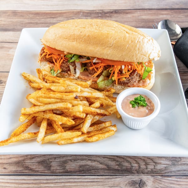 Ubuntu Bar & Grill's African-style sandwich with fries and dipping sauce on a white plate.